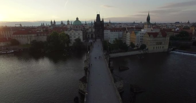 Aerial camera flies along the Charles Bridge towards the Old Town of Prague. Shot at Dawn