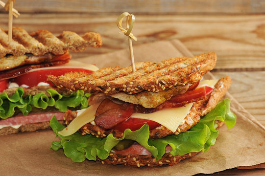 Sandwich With  Pickles On A Paper Towel On Wooden Background