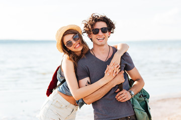 Happy hipster couple standing at the beach and hugging