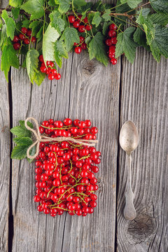 red currants like vial with twine and metal spoon and jam on wooden background, creative idea for healthy lifestyle, raw food © martingaal