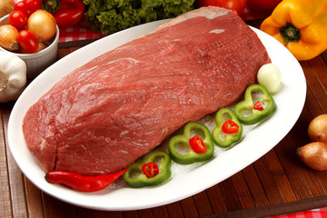 Raw meat on the plate with vegetables