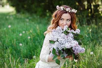 Fototapeta premium Spring beauty girl with long red hair in a white plate outdoors. Flowering tree. Romantic portrait of young woman with bouquet.