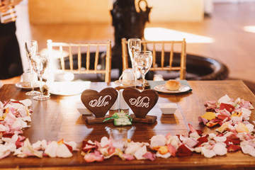Wooden table covered with petals ant decorated with woodeh heart