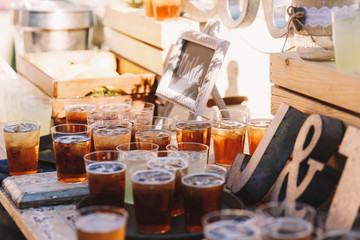 Glasses with cold cola and ice stand on the wooden table