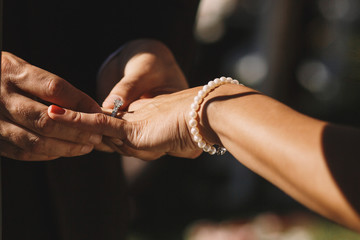 Bride holds her hand with pearl bracelet before a groom to put a