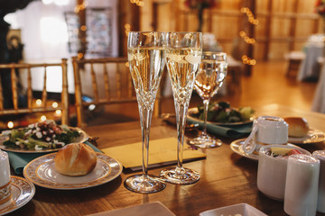 Crystal flutes with champagne stand on the wooden dinner tables