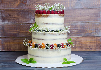 three layered wedding cake with berries and basil leaves