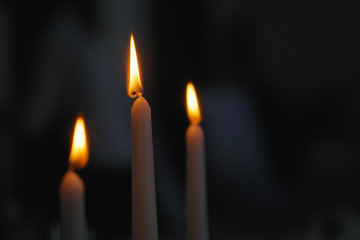 Three candles in dark room. Blurred background.