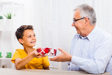 Fototapeta premium Grandson is giving present to his grandfather.