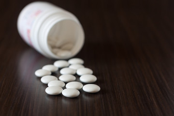 Fototapeta na wymiar Pills from a jar on a dark background