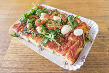 Pizza al taglio con pomodoro, mozzarella e rucola è un cibo da strada