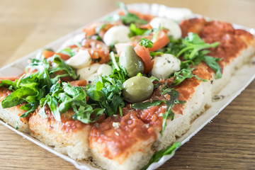 Pizza al taglio con pomodoro, mozzarella e rucola è un cibo da strada