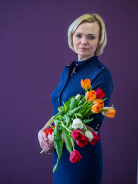 Girl in beige with flowers standing on a purple background