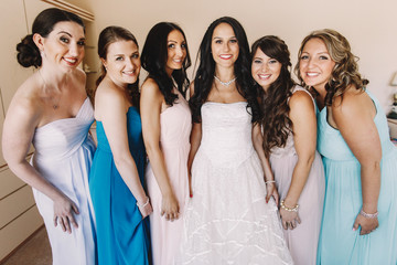 Stunning bride and bridesmaids lean to each other while posing i