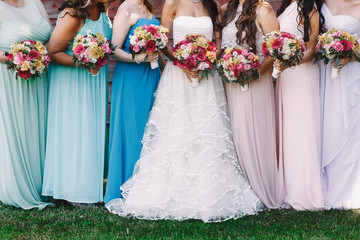 Bride and bridesmaids with bright wedding bouquets stand on the