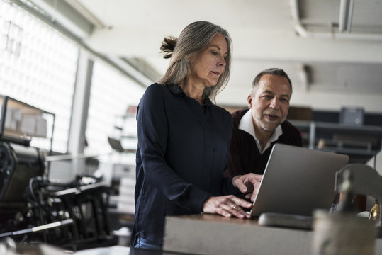 Senior Woman And Man In A Printing Shop Looking At Laptop