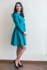 Office worker girl posing in a strict dress on wall background