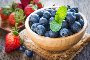 Blueberries and strawberry in wooden bowl on wooden table background