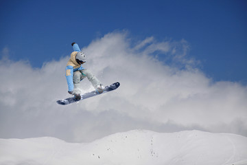 Naklejka na ściany i meble Snowboarder jumping in mountains, extreme sport.