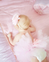 Obraz na płótnie Canvas Babygirl in pink dress lies on the blanket