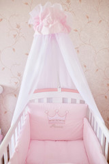 Fototapeta na wymiar White shawl hangs over the pink cradle of little girl