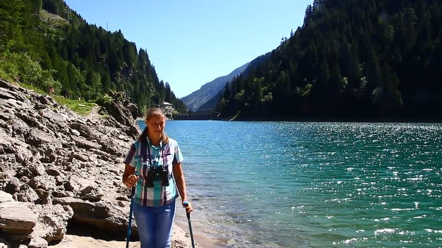 donna escursionista in riva ad un laghetto di montagna