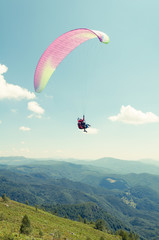 Tandem paragliding flight with hills and blue sky