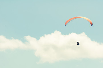 Paraglider in the blue cloudy sky