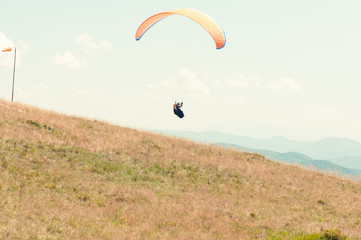 Fototapeta na wymiar Paraglider taking off from green hill