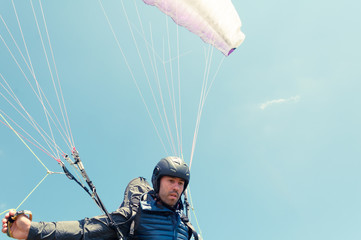 Low angle of male paraglider holding ropes - obrazy, fototapety, plakaty