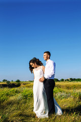 Fototapeta na wymiar Beautiful couple in field, Lovers or newlywed posing on sunset with perfect sky