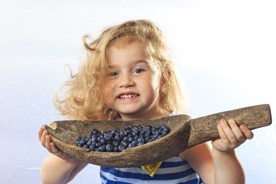 little girl holding a bucket of berries blueberries