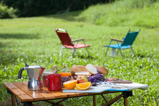 Picnic, View Of Picnic Table With Various Fruits, Juice, Pancake, Coffee And Vegetable At The Camping Area.