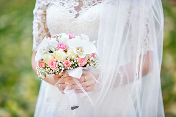 Wedding bouquet of pink roses and white orchids held by a bride