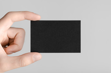 Black Business Card Mock-Up (85x55mm) - Male hands holding a black card on a gray background.