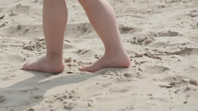 Children's legs running on the sand, slow motion