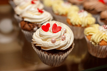 Closeup of cupcake decorated with red hearts and glaze pearls