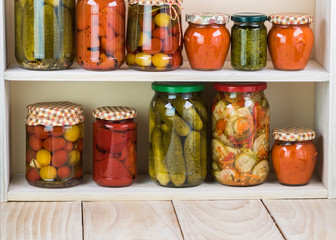 Assorted vegetable pickles in glass jars and roasted red pepper spread.