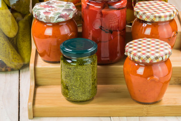 Assorted vegetable pickles in glass jars and roasted red pepper spread.