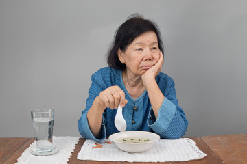 Elderly asian woman bored with food
