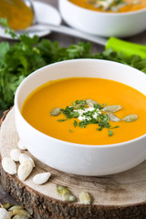 Pumpkin soup in bowl and ingredients on rustic wood
