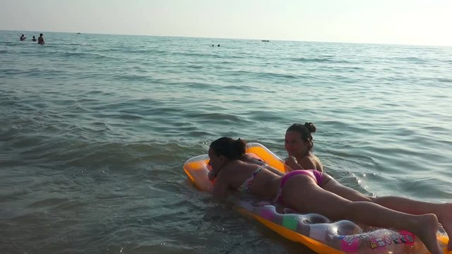  Two friends having fun  swimming on inflatable mattress 