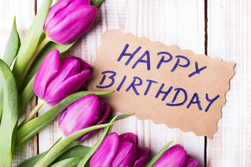 Birthday card and tulip bouquet on white wooden background