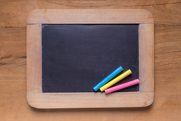 Small blackboard with color chalks on wooden background