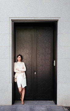 Attractive businesswoman with arms crossed standing at doorway