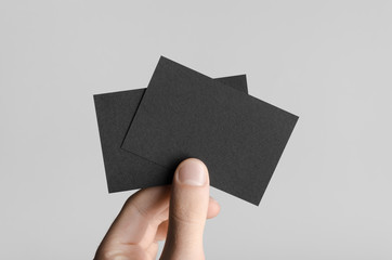 Black Business Card Mock-Up (85x55mm) - Male hands holding black cards on a gray background.