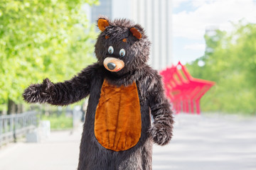 actor dressed as bear walks avenue of park on background of red stars