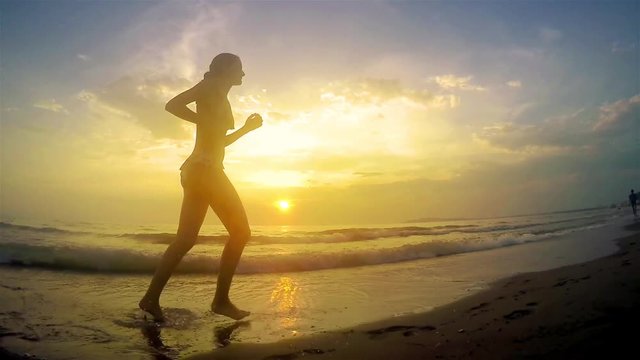 Girl model running jogging barefoot  at beach sunset, SLOW 