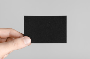 Black Business Card Mock-Up (85x55mm) - Male hands holding a black card on a gray background.