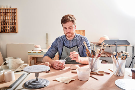 Man in workshop painting pottery